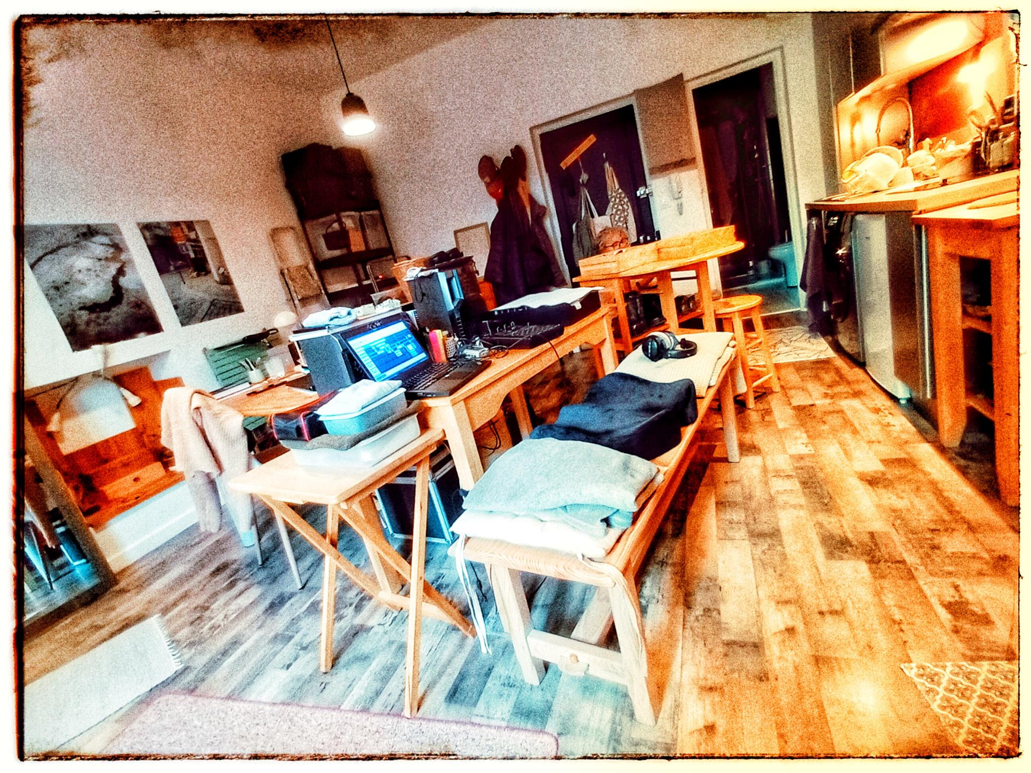 Lieu de travail avec un espace central composé de tables sur lesquels on trouve des ordinateurs et des machines pour faire de la musique.