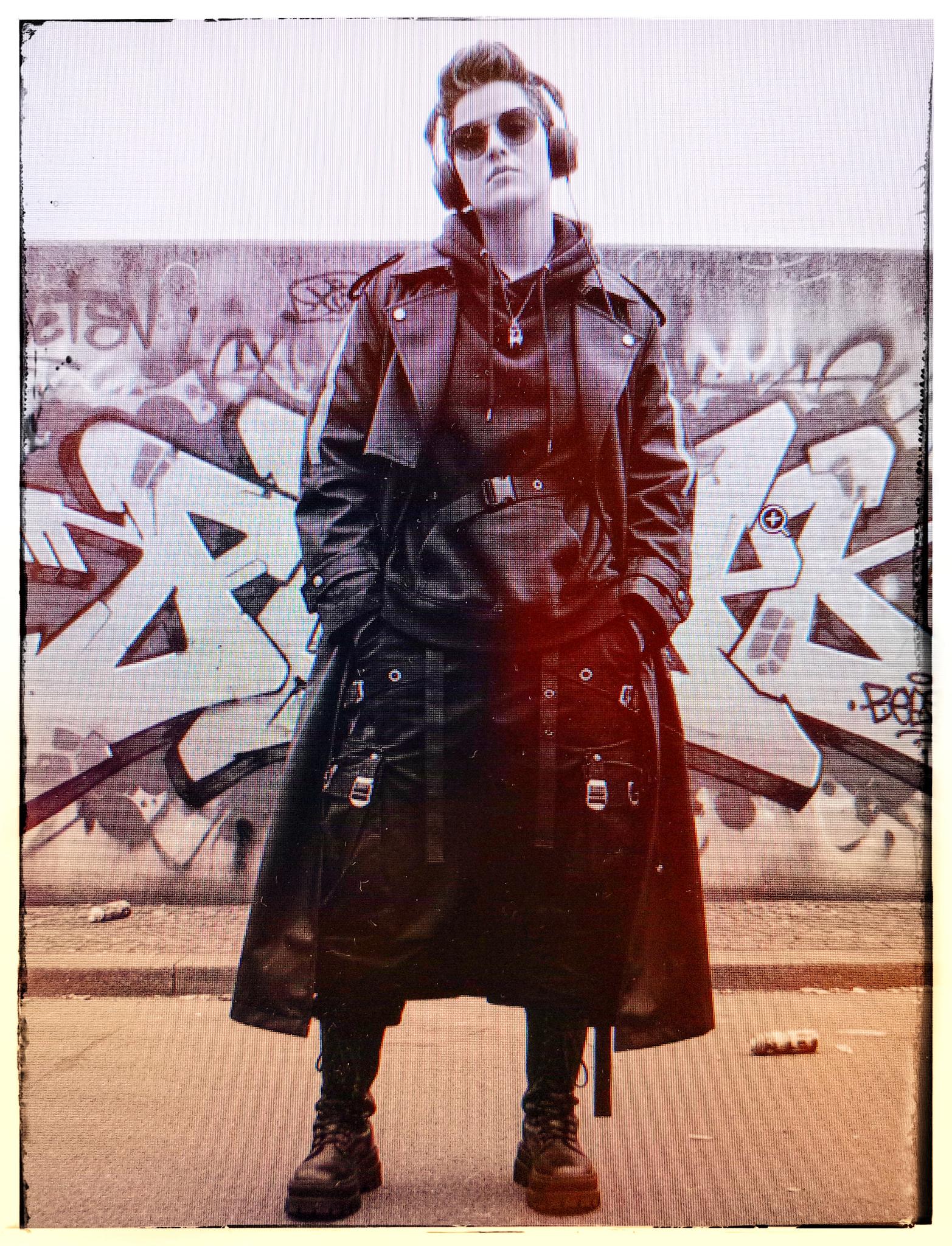 SAFY, DJ et productrice vivant à Poitiers posant de plein pied habillé en tenue cyberpunk devant un mur couvert de tags